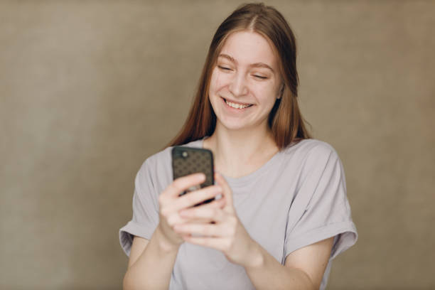 istock Young woman using mobile phone at brown background 1484082831