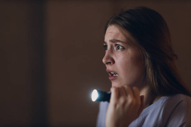 istock Woman scared holding hand flashlight in darkness and afraid of violence criminal robbery. 1484082918