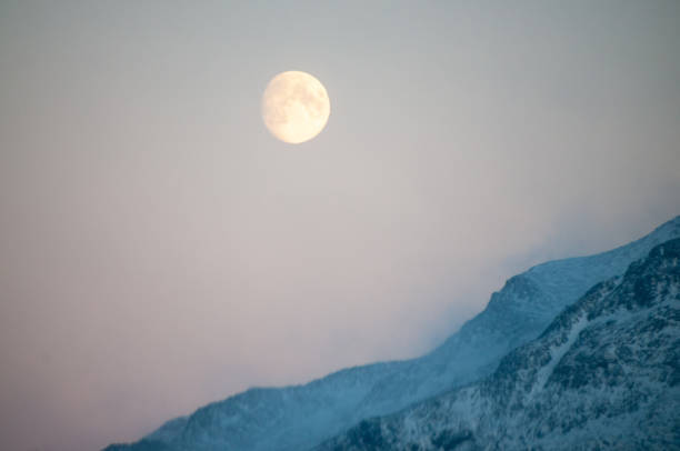istock Near full moon slipping behind a mountain 1484086549