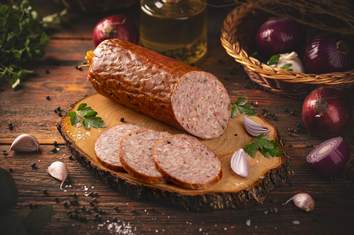 Traditional smoked salami sausage with spices on wooden board