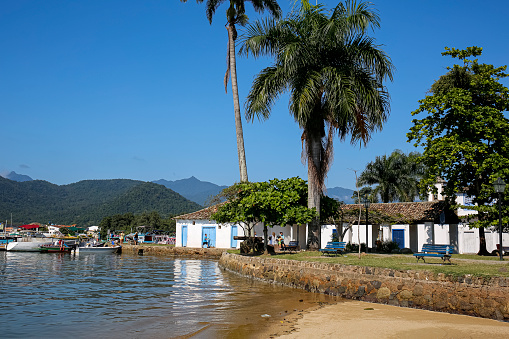 View to waterfront in historic town Paraty with colonial buildings, trees, sea and Atlantic forest mountains, Brazil, Unesco World Heritage