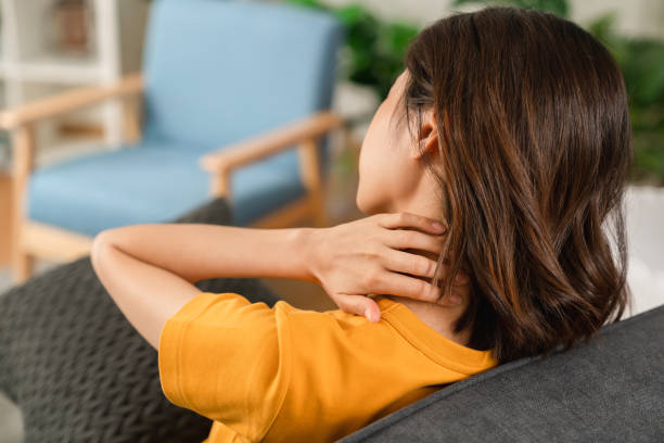 Tired young woman with neck pain and sit on the sofa at home. stock photo