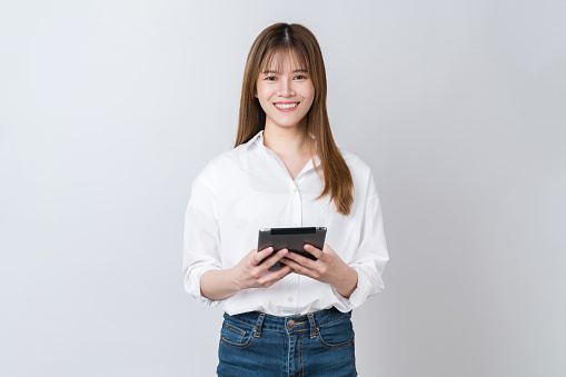 Studio shot of Beautiful Asian businesswoman holding digital tablet and smiling on white background.