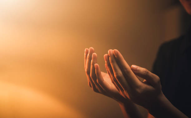 Hand praying on orange light bokeh background. stock photo