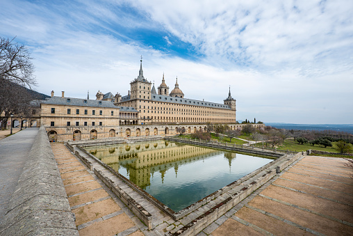 One of the facades of the Escorial monastery with a pond and views of the Madrid mountains