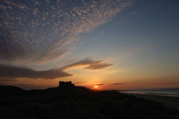 castello che si staglia al tramonto - castle bamburgh english culture old foto e immagini stock