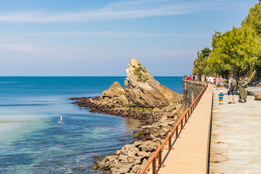 People walking on the Boulevard du Prince de Galles and rocky coast of the Cote des Basques beach in Biarritz, France