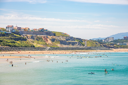 Tourists in the water and on the sandy beach of the Cote des Basques in Biarritz, France on a summer day