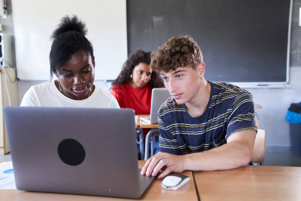 istock Students study using laptop in the classroom sitting on desk in the class together at college 1484101890