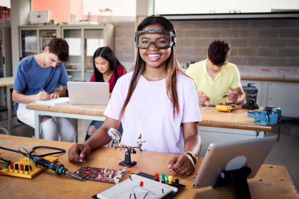 Looking at camera portrait of a young student wearing safety goggles in technical vocational training college, the lesson in High School. Education and technology concept. stock photo