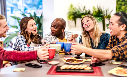 People with dog talking and having fun together at coffee restaurant - Multi racial young friends toasting coffee and doing breakfast in bar bakery shop - Friendship concept