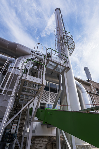 External view of the modern biomass power plant with smoking chimney on the beautiful blue sky background