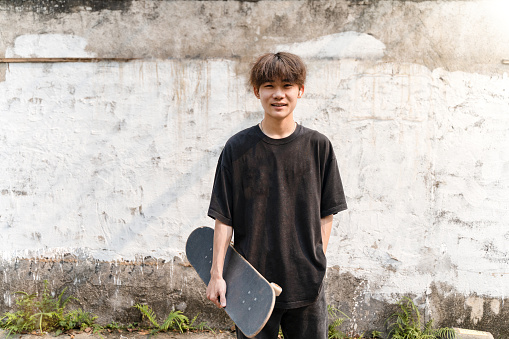 A young man skateboarding happily on the road