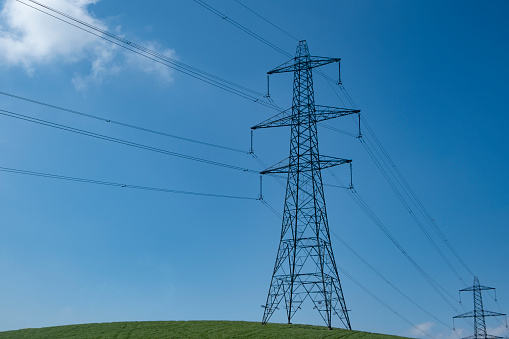A line of electricity pylons in UK countryside. With blue sky and copy space