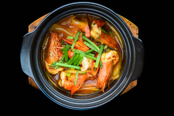istock Shrimps with vegetables in bouillon isolated on black background top view 1484108726