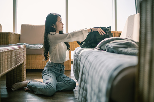Asian Chinese Teenager Female packing clothing preparing for travel in Living Room