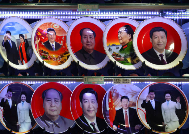 Mao and Xi on clean plates - shop window, Beijing, China Beijing, China: Souvenir plates bearing the images of China's President Xi Jinping and China's late Chairman Mao Zedong are displayed at a shop window on Tiananmen square (gift shop exterior). In some plates Xi appears with his wife, Peng Liyuan. xi jinping stock pictures, royalty-free photos & images