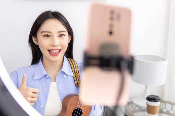 istock Young woman taking online ukulele music guitar lessons tutorial on laptop at home. Learning to play a musical instrument. 1484122427
