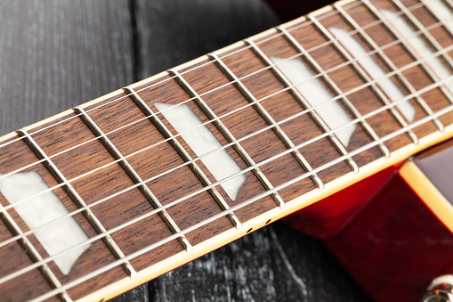 electric guitar fretboard on wood background