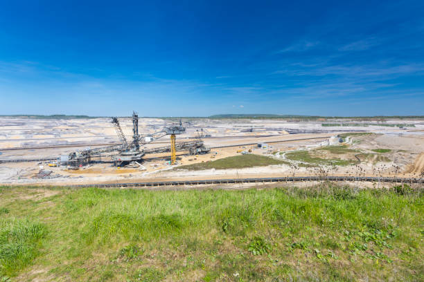 Wide view of a lignite mining area showing an open-pit coal landscape with exposed earth layers, mining infrastructure, and large-scale industrial excavation.
