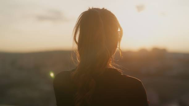 istock Young woman standing at balcony and watching sunset 1484129840