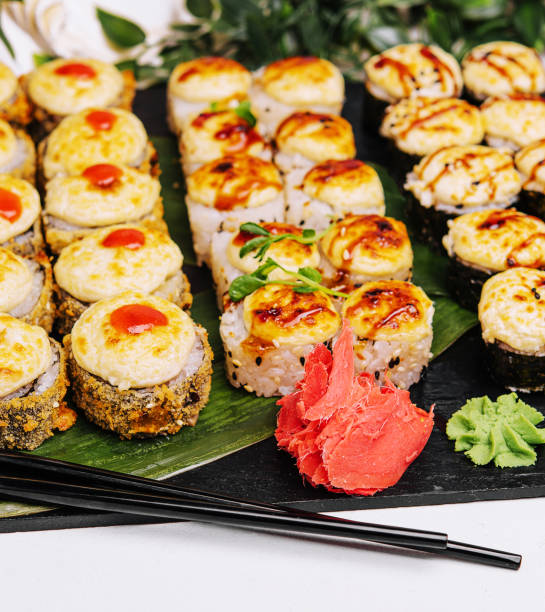 Served warm sushi with ginger and wasabi on a black stone plate