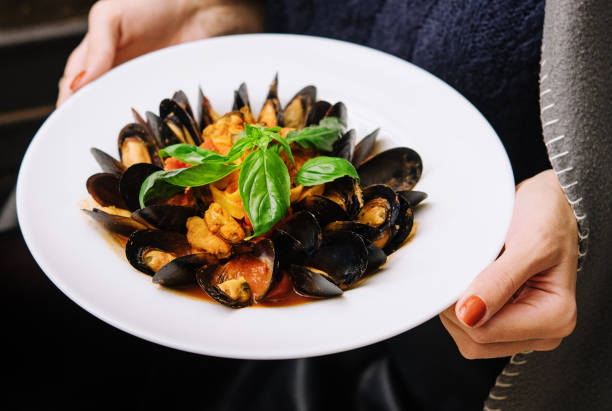 délicieuses moules fraîches cuites à la vapeur dans une sauce au vin blanc dans une assiette blanche - prepared shellfish photos et images de collection