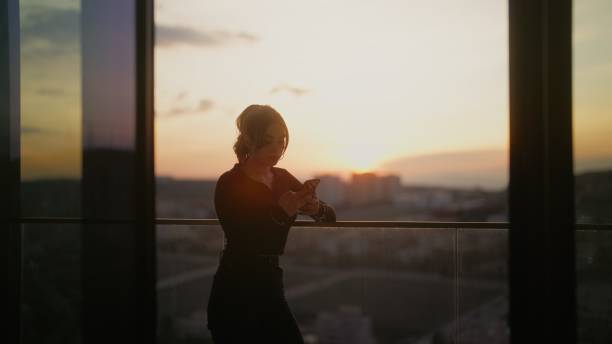 istock Young gen z woman using her smart phone at balcony during sunset 1484130506