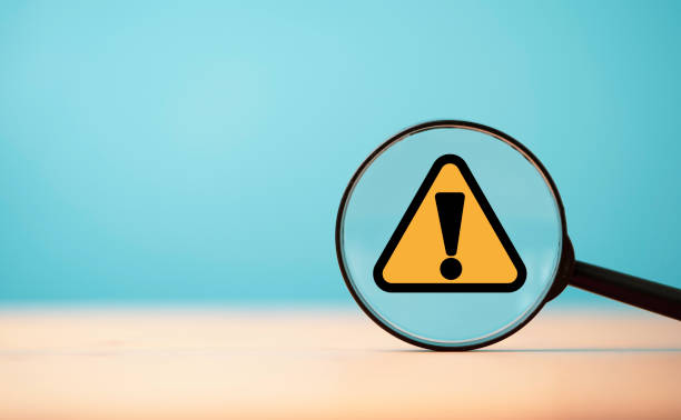 istock Yellow triangle caution warning sign inside of magnifier glass on blue background and copy space for maintenance notification error and risk concept. 1484132234