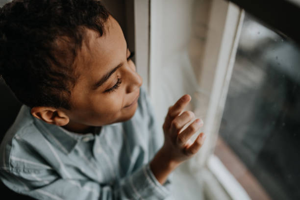 istock Little multiracial boy looking out of window. 1484132831