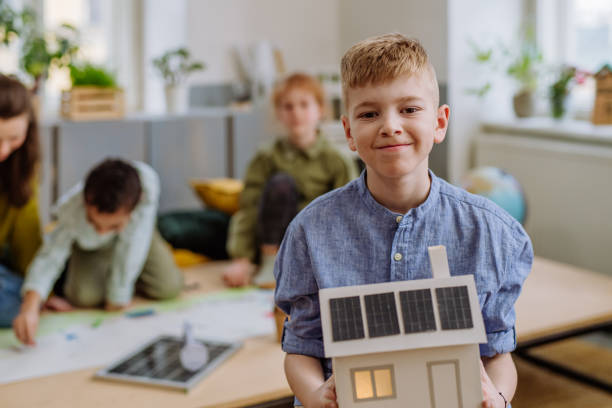 istock Little boy posing with model of house with solar system during a school lesson. 1484133381