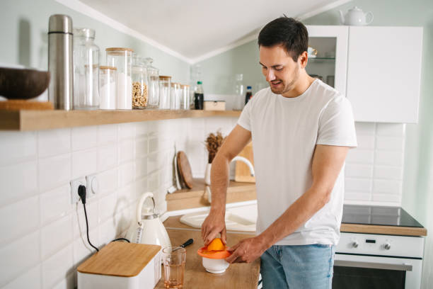 istock Man juicing orange in the kitchen 1484137208