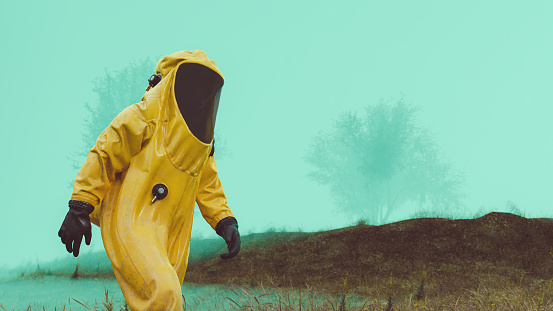 One workers wears a yellow hazmat suits for protection radiation or a virus. The worker walks in a dangerous area that has been contaminated.