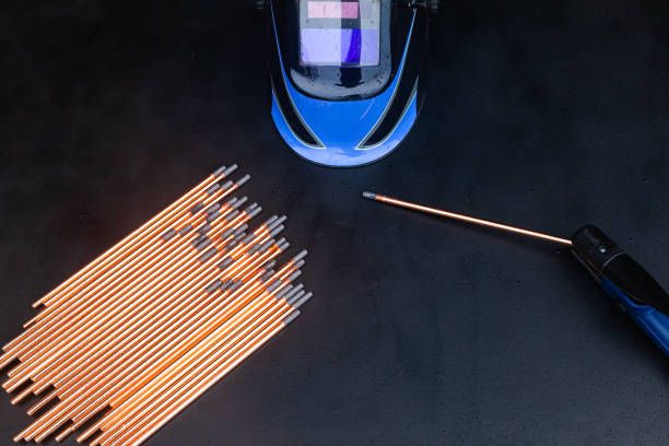 Graphite gouging electrodes with holder and welding mask on black background.