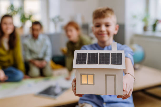 istock Little boy posing with model of house with solar system during a school lesson. 1484143889