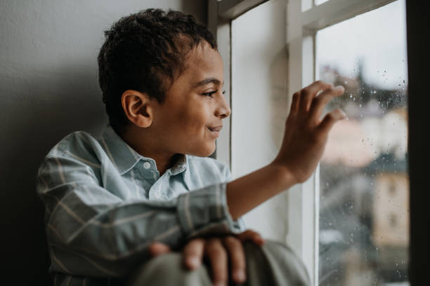 istock Little multiracial boy looking out of window. 1484143954