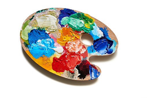 A wooden palette, with many colored gouache old stains, on white background with shadow