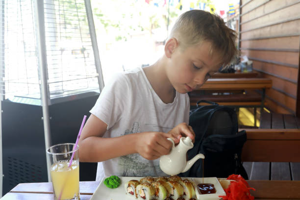 Child pouring soy sauce Child pouring soy sauce in sushi restaurant kids eating tuna stock pictures, royalty-free photos & images