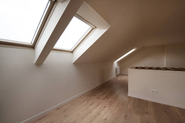 istock Empty room with chestnut flooring and cream walls with skylights in the sloping ceiling 1484149241