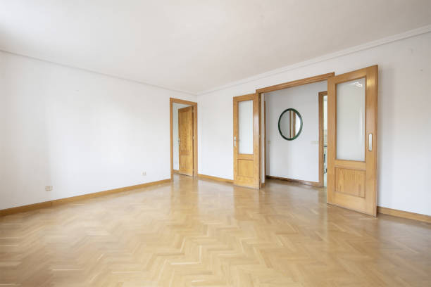 istock Empty living room with double oak doors with glass cabinets and access doors to other rooms and French oak parquet floors laid in a herringbone pattern 1484149247