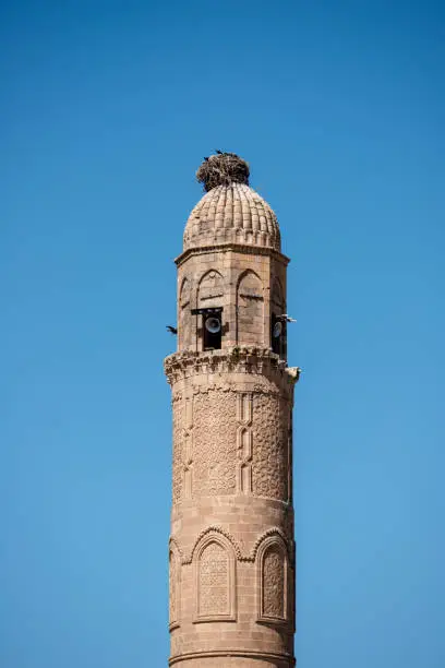 Photo of Ancient sandstone minaret with loudspeakers and storks nest on top