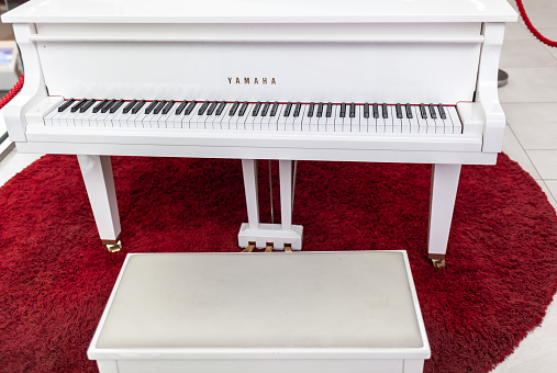 A white grand piano in a shopping mall close-up. Image for design. Space for text.