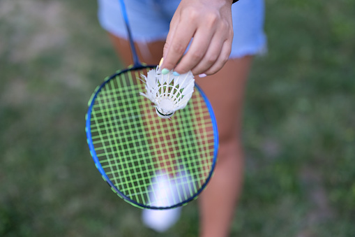 A woman is holding a badminton racket and shuttlecock and is ready to play a match.
