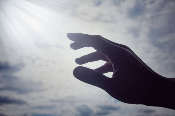istock Hand reaching out to light shining from Heaven. Religious concept 1484159968