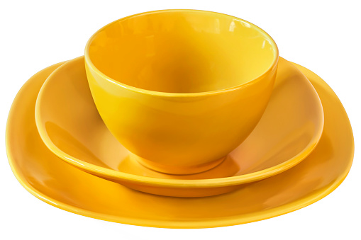 Studio shot of three pieces dinnerware set, consisted of Yellow Ceramic Soup Bowl with two matching Plates, isolated on white background, side view.