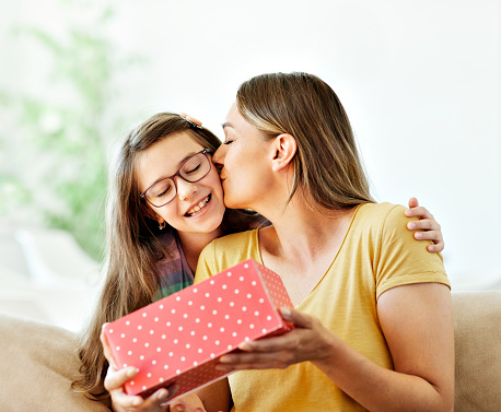 Daughter surprises her mother with present and kiss on mother's day or birthday at home