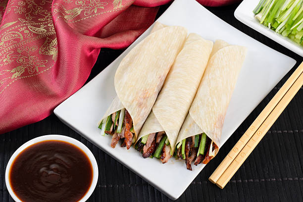 Peking Duck Wrap Chinese peking duck wrapped in pancakes with cucumber, spring onions and hoisin sauce. hoisin sauce stock pictures, royalty-free photos & images