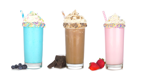 Fun colorful summer milkshakes with whipped cream isolated on a white background. Blueberry, chocolate and strawberry sweet drinks with ingredients.