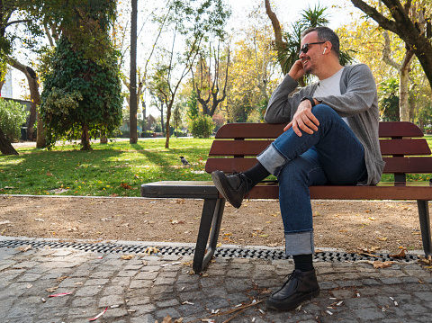 man relaxing sitting on a bench in a park