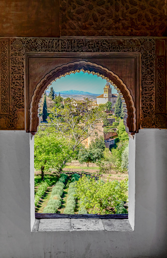 Generalife Gardens seen through a window decorated in the Arabic style.